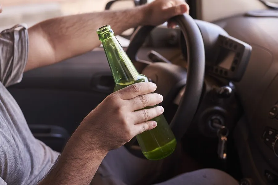 botella-cerveza-manos-hombre-conduciendo-coche-dia